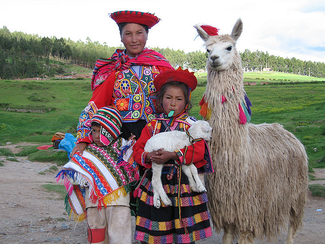 Quechua children wearing traditional clothes and holding a baby llama , Cuzco, Peru